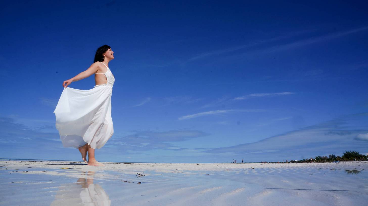 woman on beach celebrating the sun