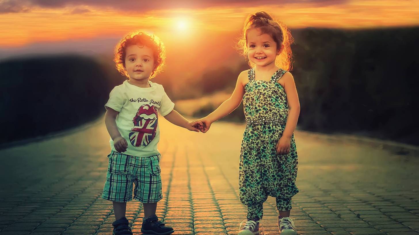 happy toddlers on sidewalk sun setting in background