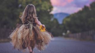 young girl in make believe dress running down the road